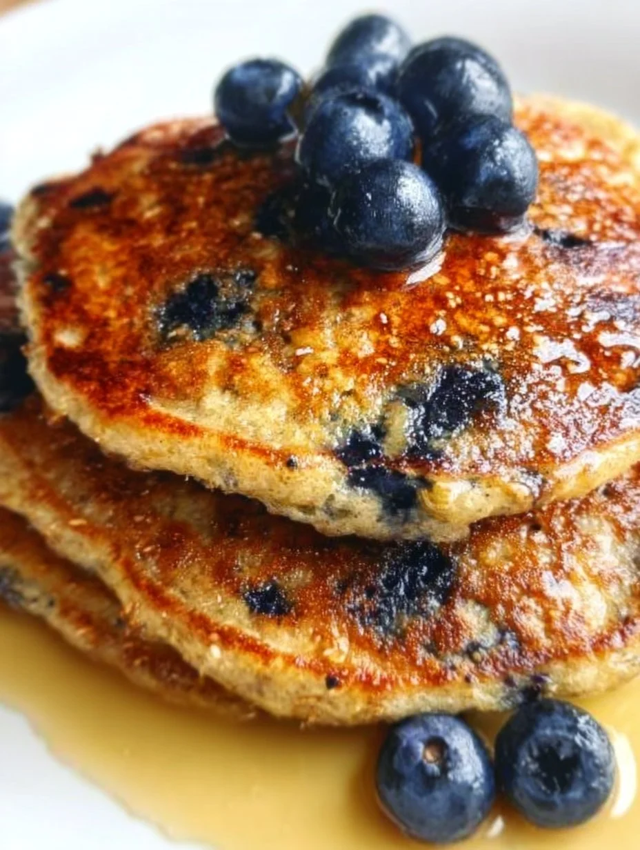 Plate of fluffy blueberry oat pancakes topped with fresh blueberries and syrup