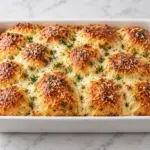 Golden garlic Parmesan pull-apart bread with mozzarella and parsley in a white rectangular dish